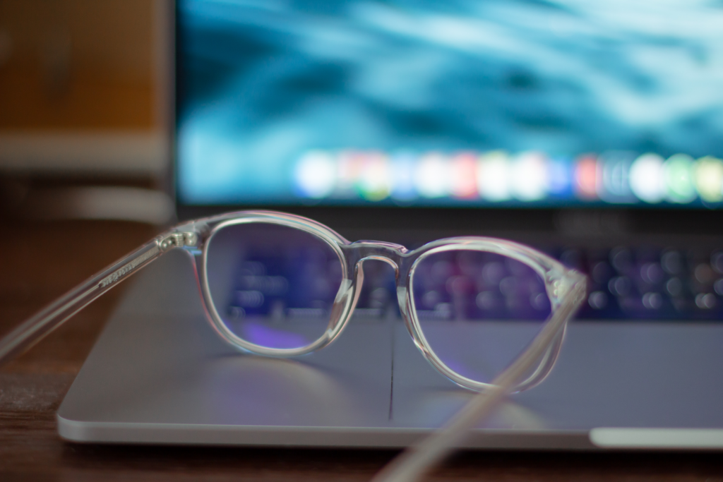 Eine durchsichtige Plastikbrille mit Blaulichtbeschichtung, die auf einem offenen Laptop sitzt